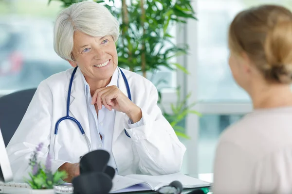 Счастливая зрелая женщина врач разговаривает с пациенткой — стоковое фото