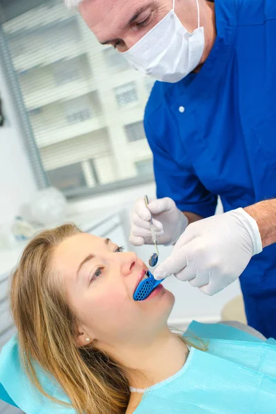 Dentista esaminando la sua bocca pazienti femminili — Foto Stock