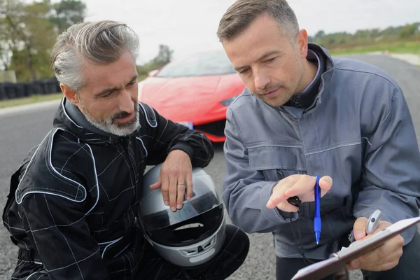 Motorista e treinador analisando a corrida — Fotografia de Stock