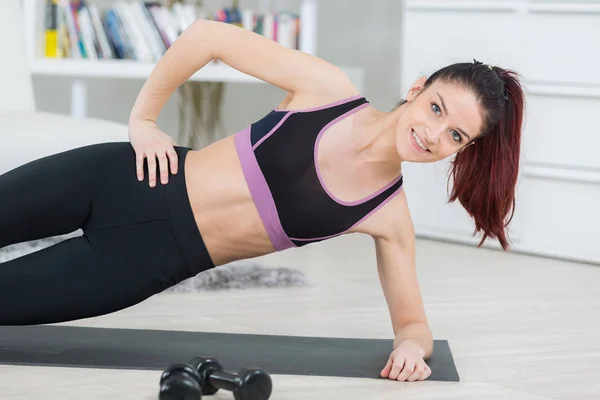 Kvinna att göra yoga i side plank pose på matta — Stockfoto