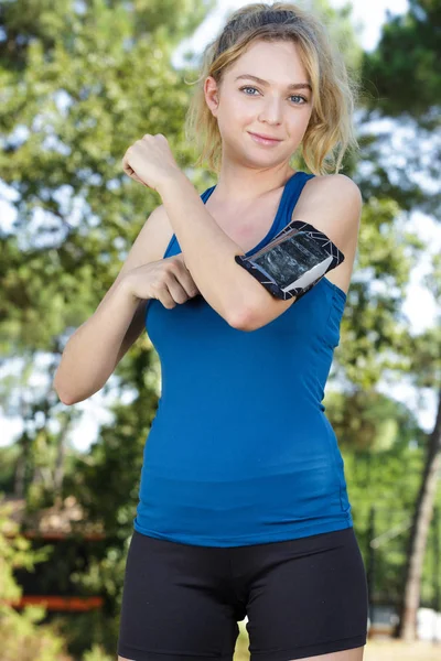 Jovem senhora garantir smartphone em braçadeira protetora — Fotografia de Stock