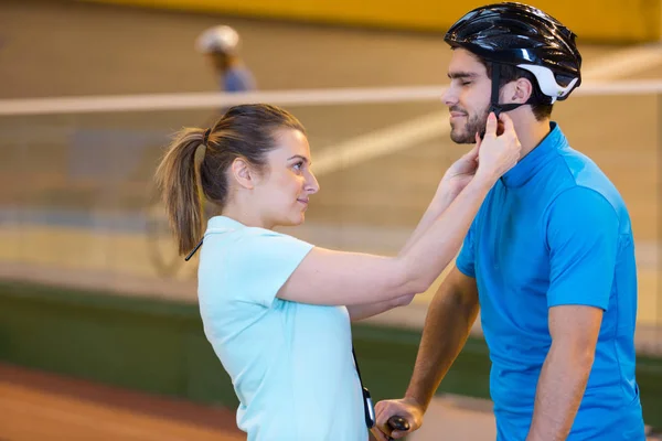 Mujer joven ayudando a su novio a ponerse el casco de bicicleta —  Fotos de Stock