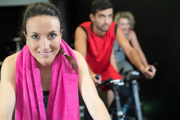 Ženy a muži na kole v tělocvičně pro fitness — Stock fotografie