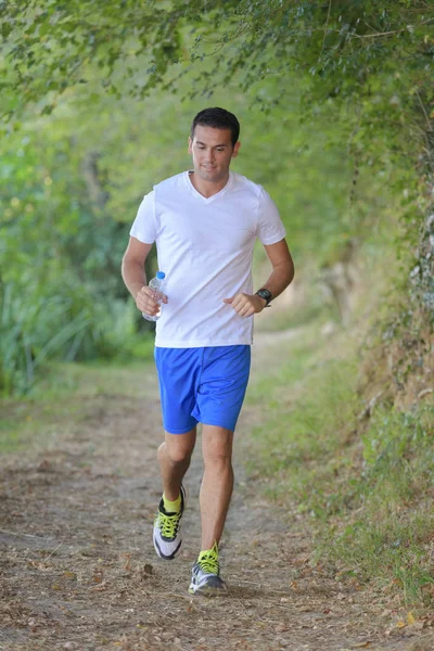 Young man jogging along country path — Stock Photo, Image