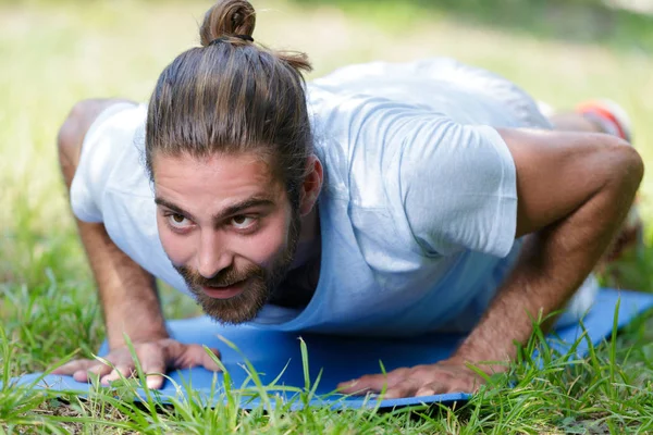 Muž v prkně cvičení pozice na podložce venku — Stock fotografie