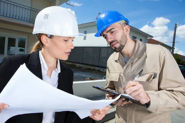 Vrouwelijke site manager met werknemer het maken van notities op klembord — Stockfoto