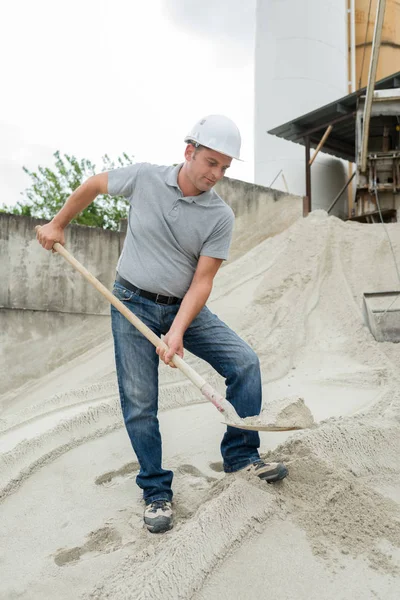 Muž vezme lopatu písku — Stock fotografie