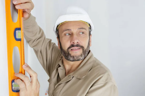 Handwerker mit Wasserwaage an Wand — Stockfoto