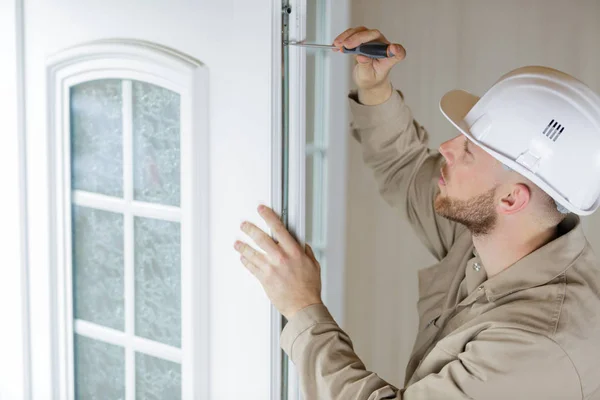 En ung hantverkare reparerar ett fönster — Stockfoto