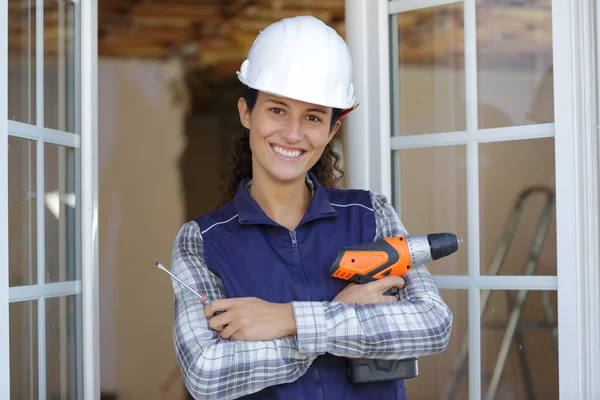 Mutlu kadın inşaatçı duvarda sondaj yapıyor. — Stok fotoğraf