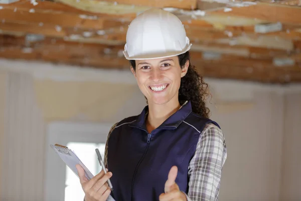 Woman builder holding clipboard shows thumb up — Stock Photo, Image