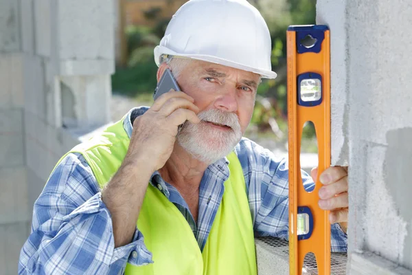 Constructor senior en la pared de medición del teléfono — Foto de Stock