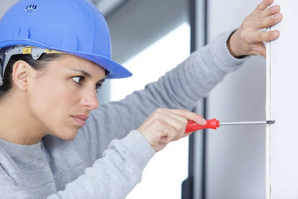 Handwerkerin schraubt an der Wand — Stockfoto