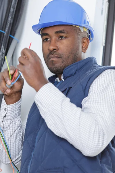 Ein männlicher Elektriker inspiziert die Verkabelung — Stockfoto