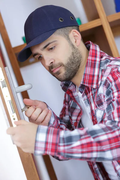 Jovem consertando a porta — Fotografia de Stock