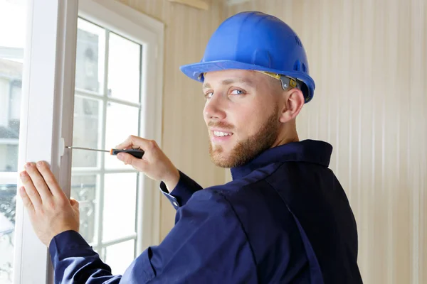 Professioneller Bauunternehmer mit Schraubenzieher am Fenster — Stockfoto