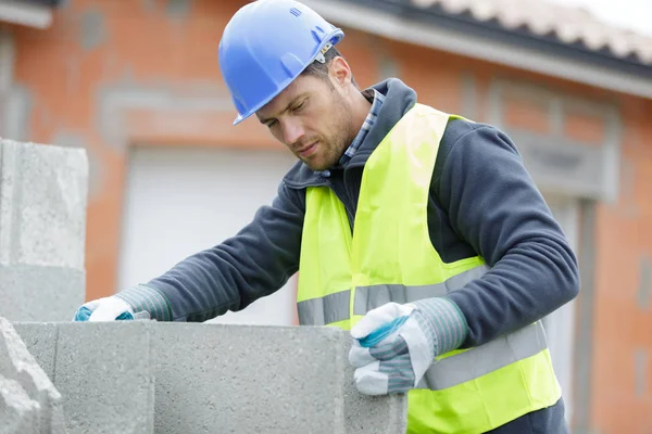 Byggmästare med betongblock för husbyggnad — Stockfoto