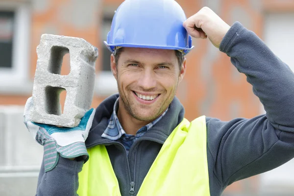 Confident handsome builder helmet carrying a cement block — Stock Photo, Image