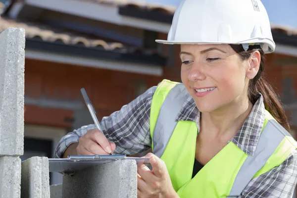 Young smiling builder writing on clipboard — Stock Photo, Image