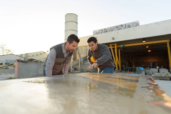 2 hombres piedra corte fábrica chequeo pieza de mármol otudoors —  Fotos de Stock