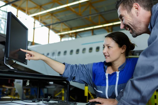 Kadın uçak tamircisi dizüstü bilgisayarı işaret ediyor — Stok fotoğraf