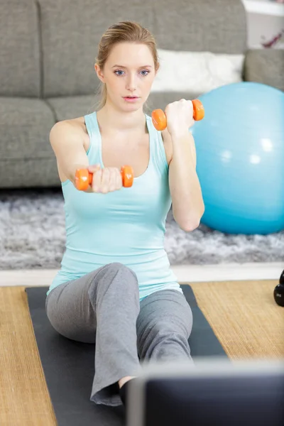 Bela mulher fazendo exercício com dumbbells enquanto assiste tv — Fotografia de Stock