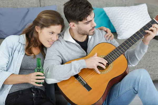 Evde gitar çalan sevimli genç bir çift. — Stok fotoğraf