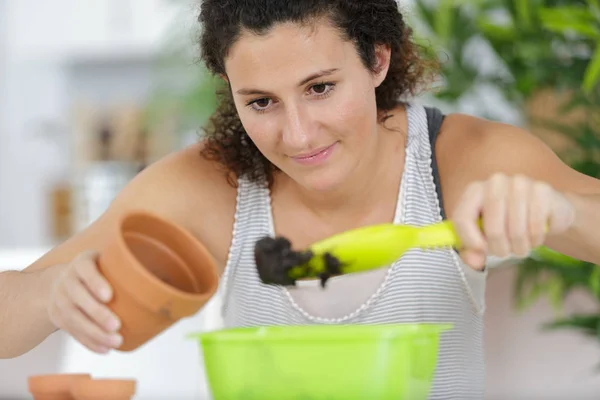 Sorrindo jovem ceramista feminina segurando planta — Fotografia de Stock