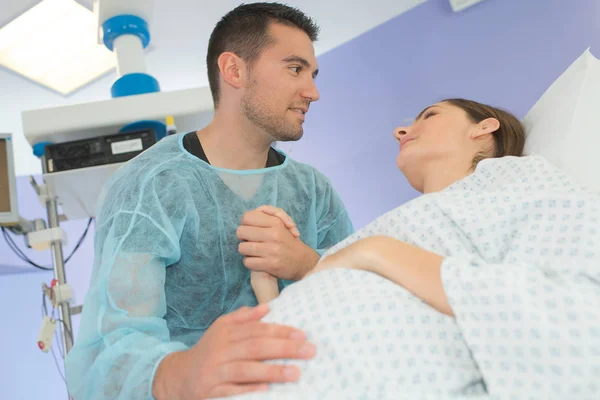 Husband supporting wife giving birth in hospital — Stok fotoğraf