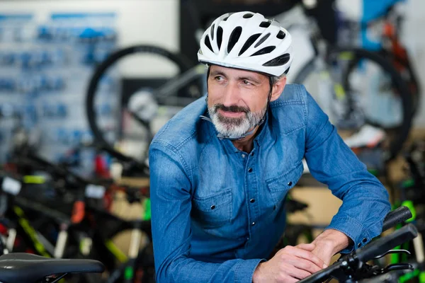 Uśmiechnięty mężczyzna wybierający nowy rower sportowy i kask ochronny — Zdjęcie stockowe