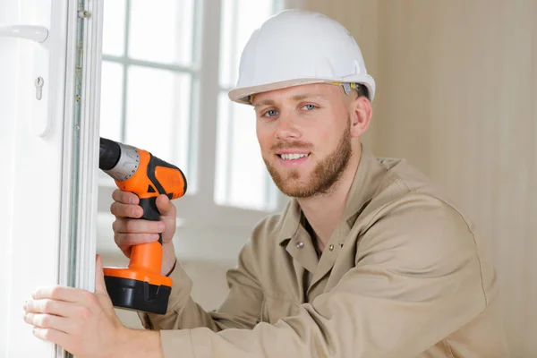 Young male contractor using drill on pvc door — Stock Photo, Image