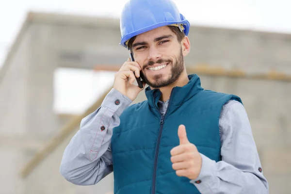 Bonito construtor mostrando polegares para cima e rindo — Fotografia de Stock