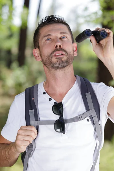 Traveler man looks through a binoculars — Stock Photo, Image