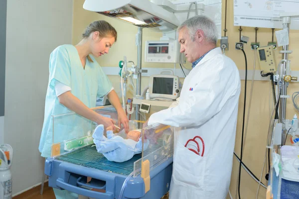 Медсестра і лікар перевіряють дитину в інкубаторі — стокове фото