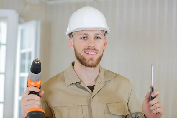Portrait of a builder in working uniform standing with drill — Stok fotoğraf