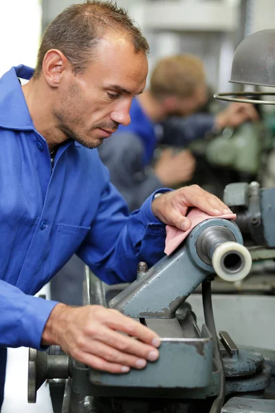 Lärling med hjälp av maskiner i fabrik — Stockfoto
