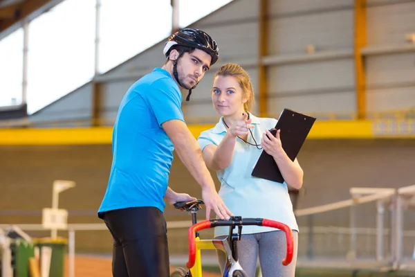 Női edző kerékpárossal velodrómban — Stock Fotó