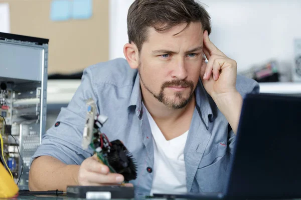 En manlig arbetare undersöker bärbar dator — Stockfoto