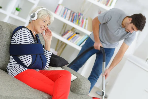 Senior Vrouw Zitten Bank Terwijl Thuis Hulp Het Schoonmaken — Stockfoto