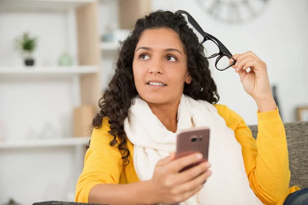 Mujer Joven Sosteniendo Sus Gafas Mientras Usa Teléfono Inteligente —  Fotos de Stock