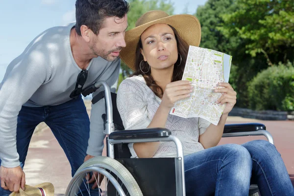 坐在轮椅上的丈夫和女人看地图 — 图库照片
