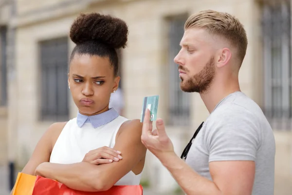 young woman annoyed as man holds credit card while shopping