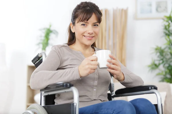 坐在轮椅上笑着喝咖啡的女人 — 图库照片