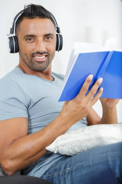 Hombre Barbudo Sonriente Con Libro Auriculares Sentados Sofá —  Fotos de Stock