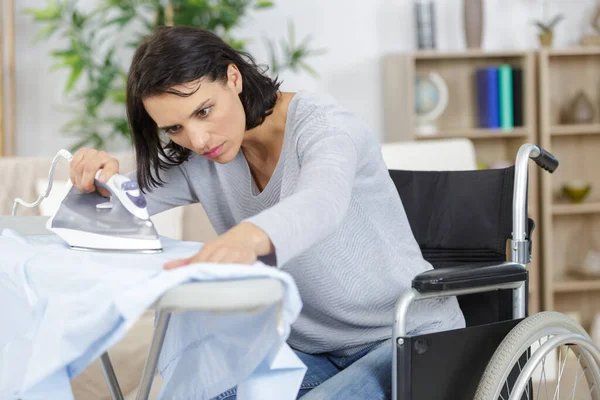 Vrouw Rolstoel Tijdens Het Strijken Thuis — Stockfoto