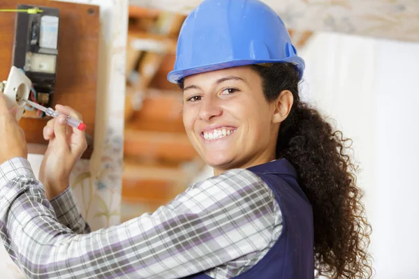 室内安装螺丝起子插座的快乐女建筑工人 — 图库照片