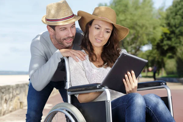 Пара Смотрит Планшетную Женщину Инвалидном Кресле — стоковое фото