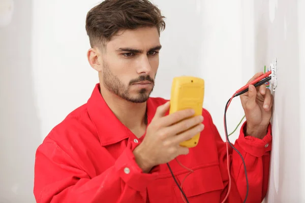 Mladý Muž Elektrikář Pomocí Multimetru Pro Testování Zásuvky — Stock fotografie