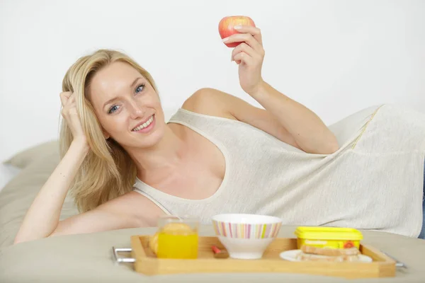 素敵な女の子がベッドでリンゴを食べる — ストック写真
