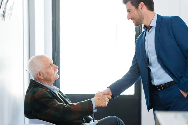 Geschäftsmann Begrüßt Seniorin Wartezimmer — Stockfoto